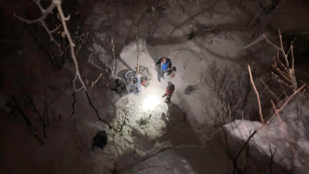 Des grimpeurs sur glace se préparent dans la noirceur avec des lampes frontales.