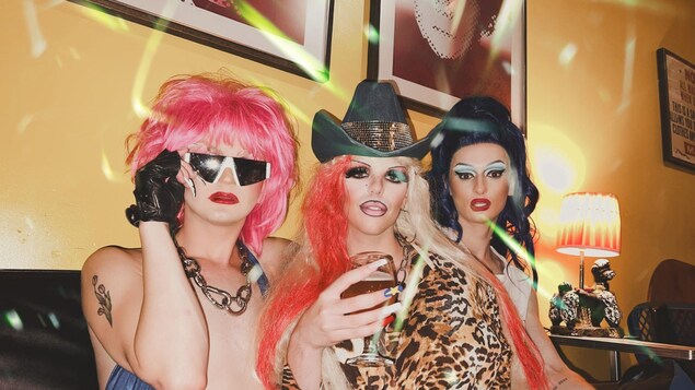Les trois drag queens, Chiquita Mére, Sami Landri et Rose Beef assises ensemble, posant pour une photo.