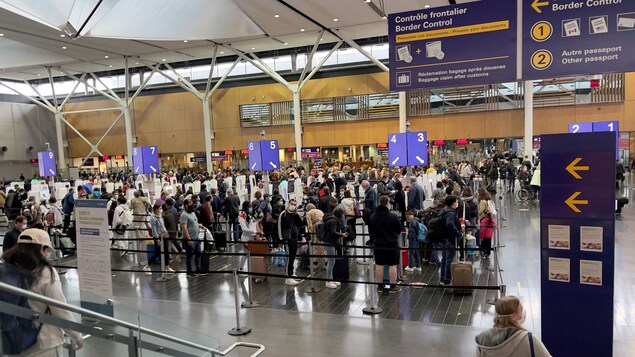 Des gens font la file avec leurs bagages pour passer le contrôle frontalier à l'Aéroport international Pierre-Elliott-Trudeau de Montréal.