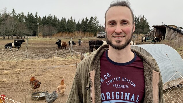 Antoine Robillard pose pour la photo devant des poules.