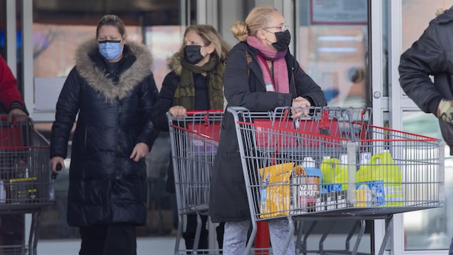 Des gens masqués sortent d'un magasin à grande surface après avoir faire des emplettes. 