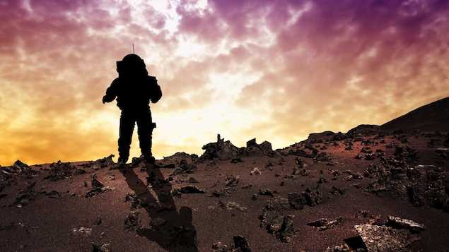 Silhouette d'un astronaute sur un terrain rocailleux.