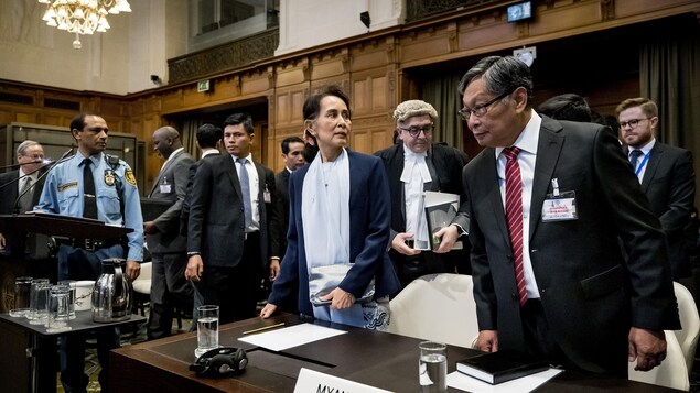 Aung San Suu Kyi est debout dans la salle d'audience, entourée d'autres responsables birmans.