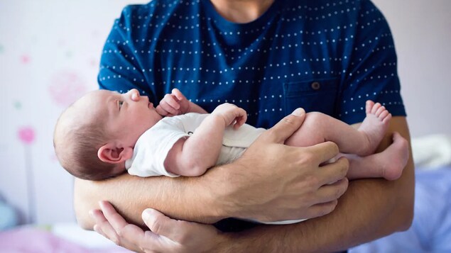 Un homme berce un bébé dans ses bras.