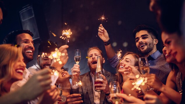 Des jeunes gens trinquent et fêtent avec abandon dans un club de nuit.