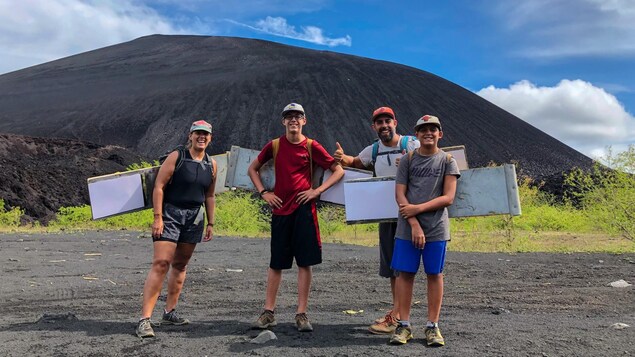 Un couple dans la trentaine et ses deux fils, portant chacun une casquette, devant le volcan Cerro Negro, au Nicaragua.