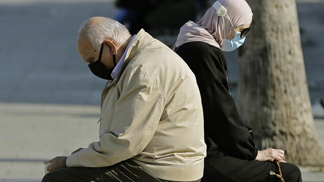 Un homme et une femme assis sur un banc public de la Corniche de Beyrouth tiennent des komboloïs.