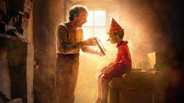 Roberto Benigni incarne Geppetto qui montre un objet à sa création de bois Pinocchio.
