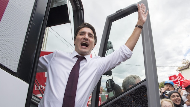 Justin Trudeau salue le public dans l'embrasure d'un autobus durant la campagne électorale de 2015.