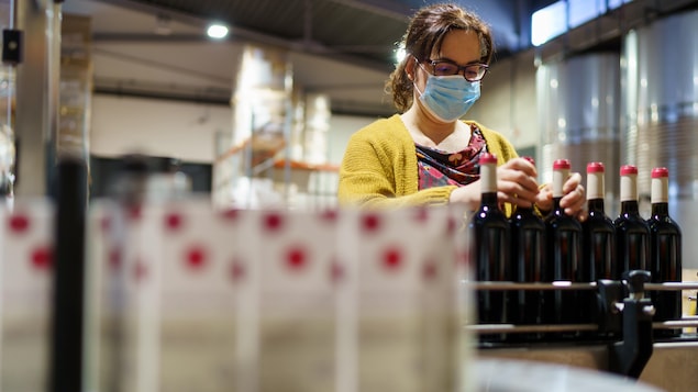 Dans une usine espagnole, une employée embouteille du vin. 