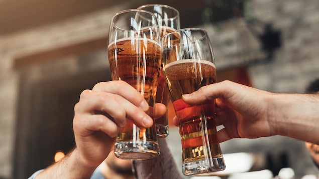 Gros plan sur des verres de bières d'amis qui trinquent. 