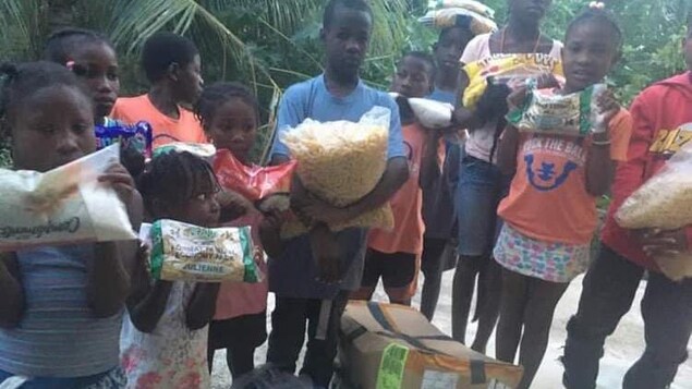 Des enfants haïtiens avec des denrées plein les mains.