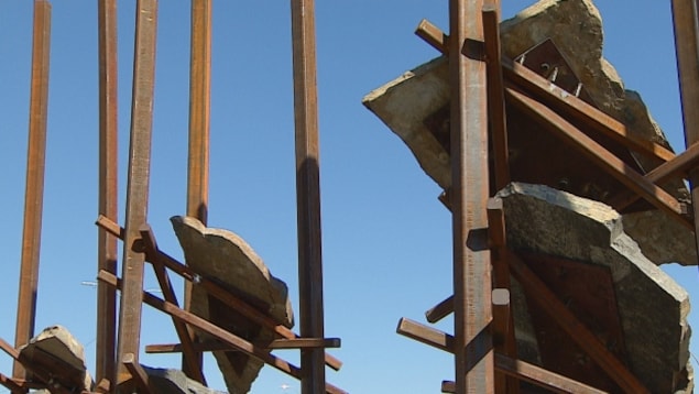 Des poutres de métal rouillé avec des plaques de pierres suspendues