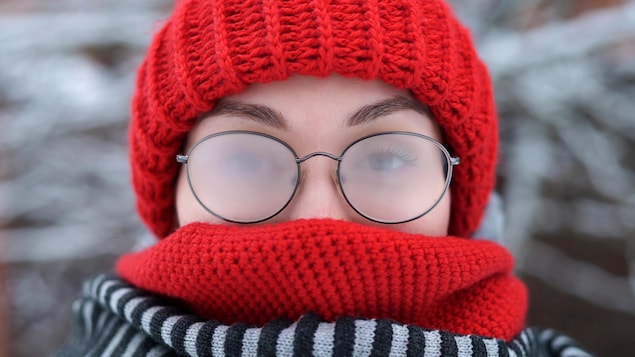Portrait d'une jeune femme qui porte des verres embués à l'extérieur, par une journée glaciale et enneigée.