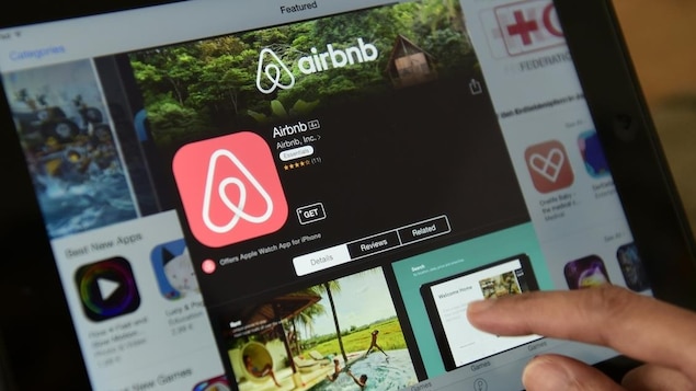 Un aperçu de l'application Airbnb sur une tablette où l'on voit le logo et une photo de piscine. 