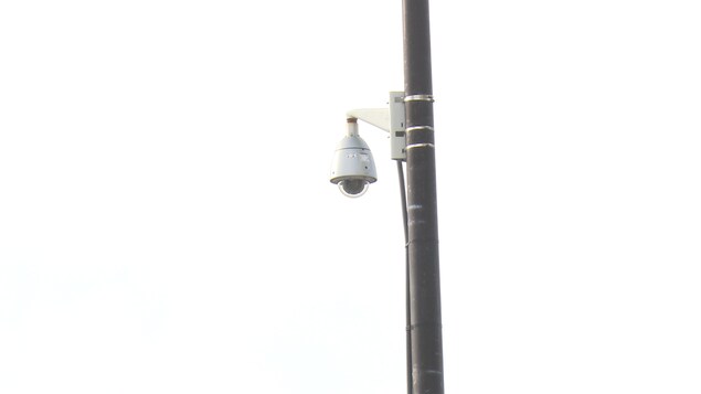 Une petite caméra rotative attachée à un poteau de lumière situé en plein centre-ville. Une petite caméra rotative attachée à un poteau de lumière situé en plein centre-ville.