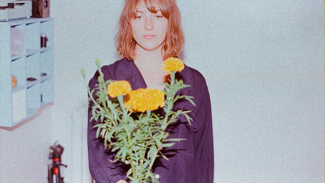 Une femme tient un bouquet de fleurs.