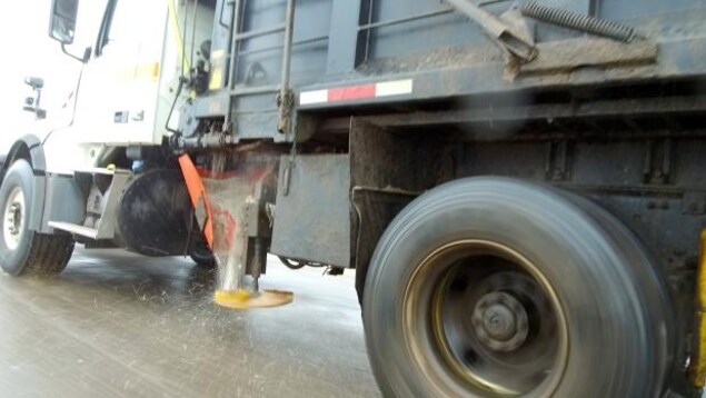 Un camion répand du sel sur une route.