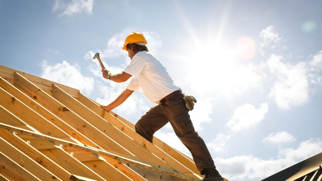 Un ouvrier sur une charpente de toit. 