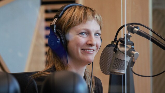 Elle sourit au micro, casque d'écoute sur la tête, assise dans le Studio 1 de la nouvelle Maison de Radio-Canada. 