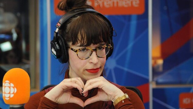 Catherine Ethier forme un cœur avec ses mains lors d'une intervention dans un studio de radio. 