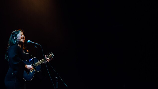 une chanteuse joue de la guitare sur scène