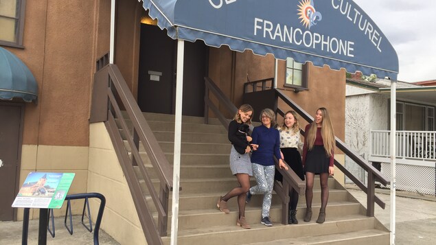 Quatre employées posent dans les escaliers de l'édifice qui abrite le Centre culturel francophone de l'Okanagan, situé à Kelowna.