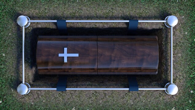 Un cercueil est déposé en terre, prêt à être enseveli.