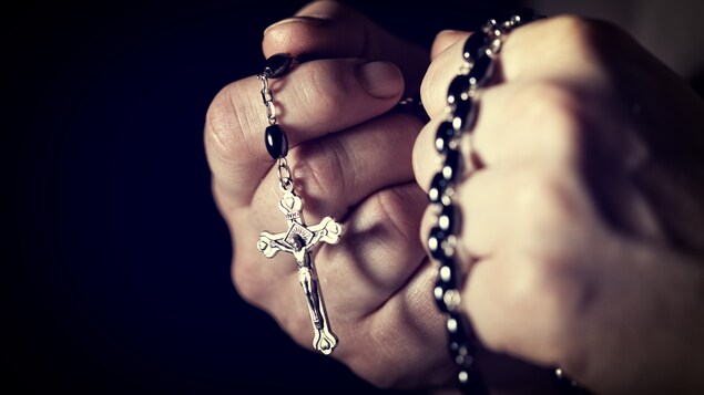Un chapelet avec la croix de Jésus, dans les mains d'une personne.