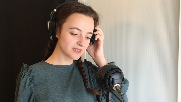 Charlotte Côté porte les écouteurs et fait face à un micro.