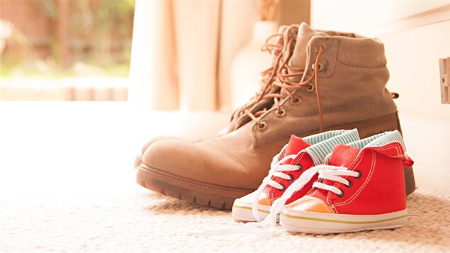 Des bottes de militaire à côté de petits souliers pour enfants. Des bottes de militaire à côté de petits souliers pour enfants.