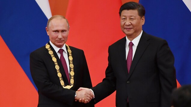 Le président russe Vladimir Poutine et le président chinois Xi Jinping se serrent la main. 