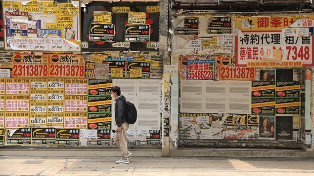 Un jeune homme marche devant une enseigne en Chine. 