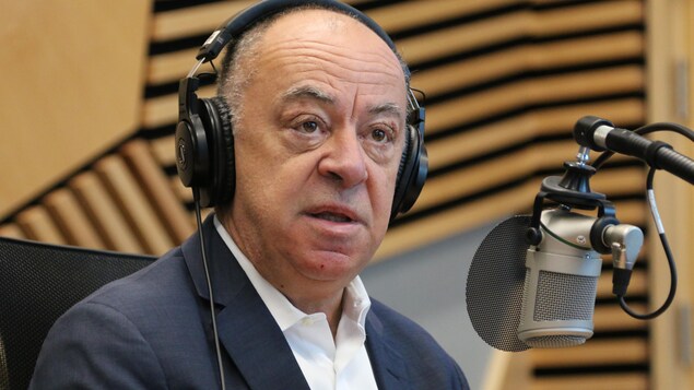 Un homme, casque d'écoute sur la tête, parle dans un micro lors d'une entrevue à la radio. 