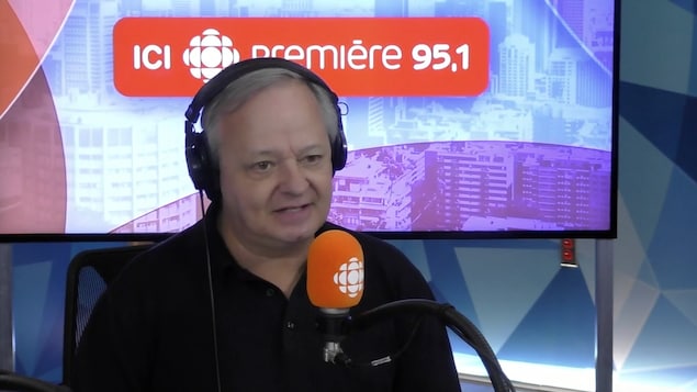 Christian Larouche derrière un micro dans un studio radio de Radio-Canada.