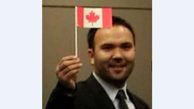 Portrait de Huseyin Celil tenant un petit drapeau canadien à la main