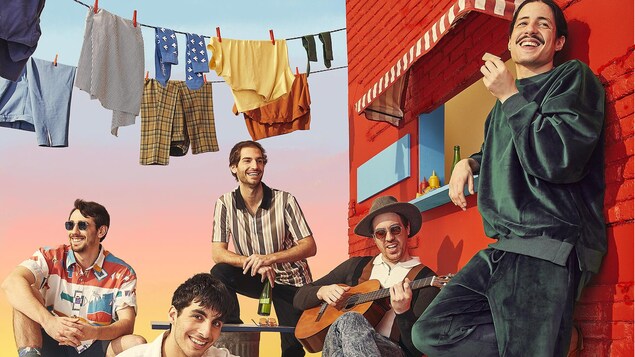 Les cinq membres du groupe en hauteur sur un immeuble de couleur rouge, avec une corde à linge en arrière-plan.