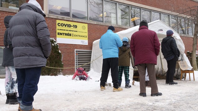 Des gens font la queue devant une clinique de dépistage de la COVID-19, à Montréal.