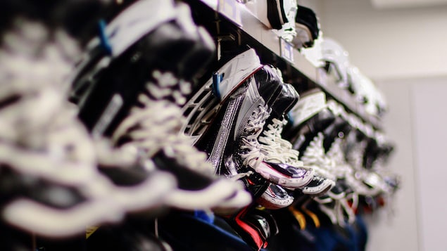 Gros plan sur des patins à glace et l'équipement de hockey d'une équipe dans un vestiaire. 