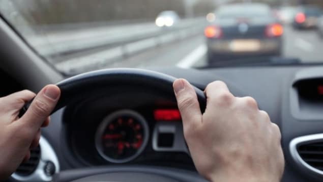 Des mains sur un volant dans une voiture.