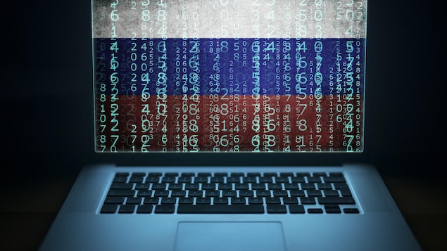 Un ordinateur portable affichant du code informatique binaire avec un drapeau russe en filigrane sur l'écran. 