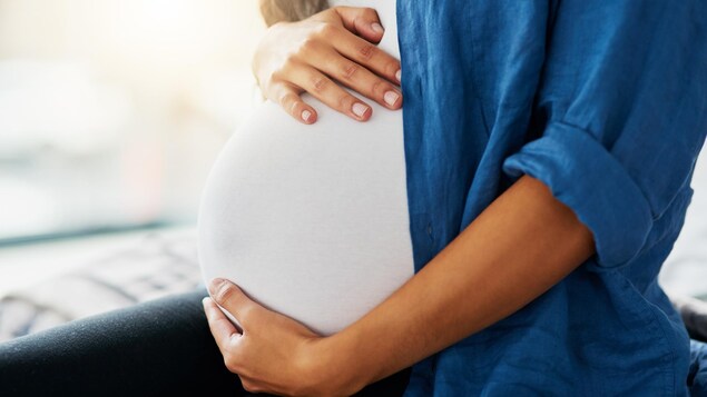 Une femme enceinte se tient le ventre.