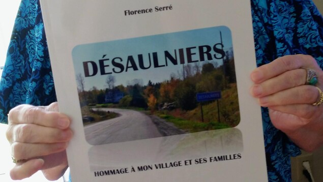 Florence serré qui tient son livre dans ses mains. On peut y lire le titre: Désaulniers, hommage à mon village et ses familles. 
