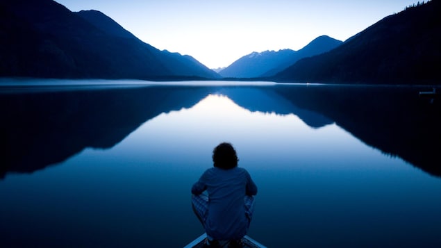 Une personne regarde un lac silencieux.