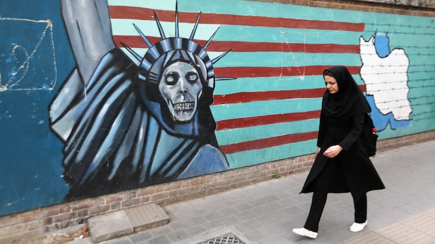 Une femme marche devant un mur de l'ex-ambassade américaine de Téhéran.