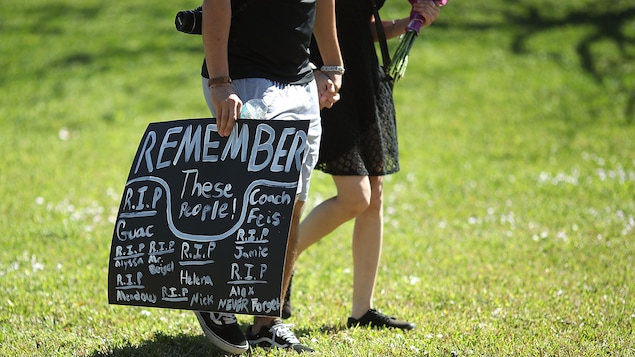 Une personne transporte une pancarte sur laquelle il est inscrit en anglais: Souvenez de ces victimes Une personne transporte une pancarte sur laquelle il est inscrit en anglais: Souvenez de ces victimes