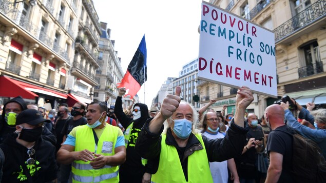 Des hommes portant un gilet jaune et des pancartes dénonçant la situation socio-économique en France.