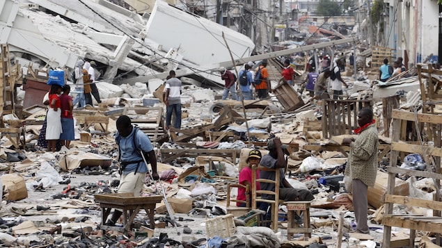 Des résidents marchent dans une rue encombrée de débris de maison à Port-au-Prince après le tremblement de terre de 2010