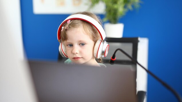 Une petite fille devant un écran d'ordinateur à la maison lors de l'un de ces cours à distance