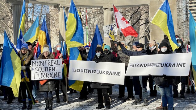Des manifestants en soutien avec l'Ukraine tenant des drapeaux ukrainiens et canadiens, des pancartes dénonçant Poutine.
